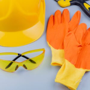 close-up view of pattern from set of construction tools as safety glasses safety helmet putty knife and gloves on gray background