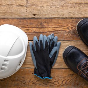 Work helmet, boots and gloves on a wooden background, top view, construction and special clothing concept.